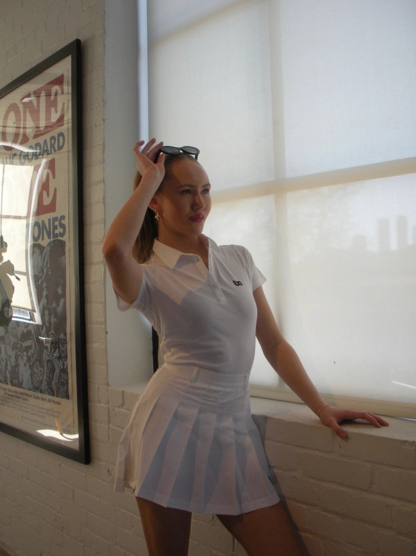 Woman wearing white BOV Active BA pleated skirt by the window