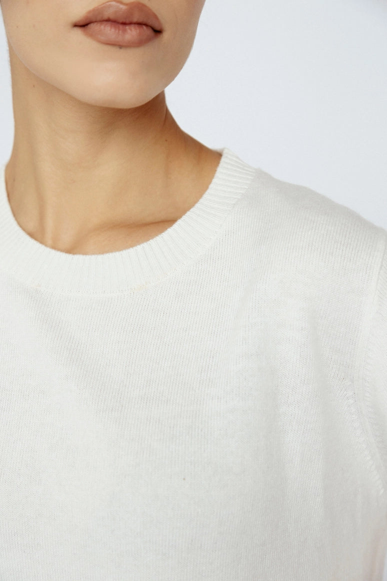 Close-up of a person wearing a white sweater against a plain background Amanda Maria