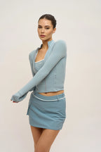 Woman wearing a light blue athletic outfit on a plain background