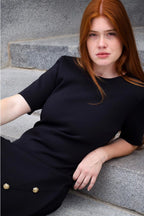 Woman in a black dress sitting on stone steps. ANNICK