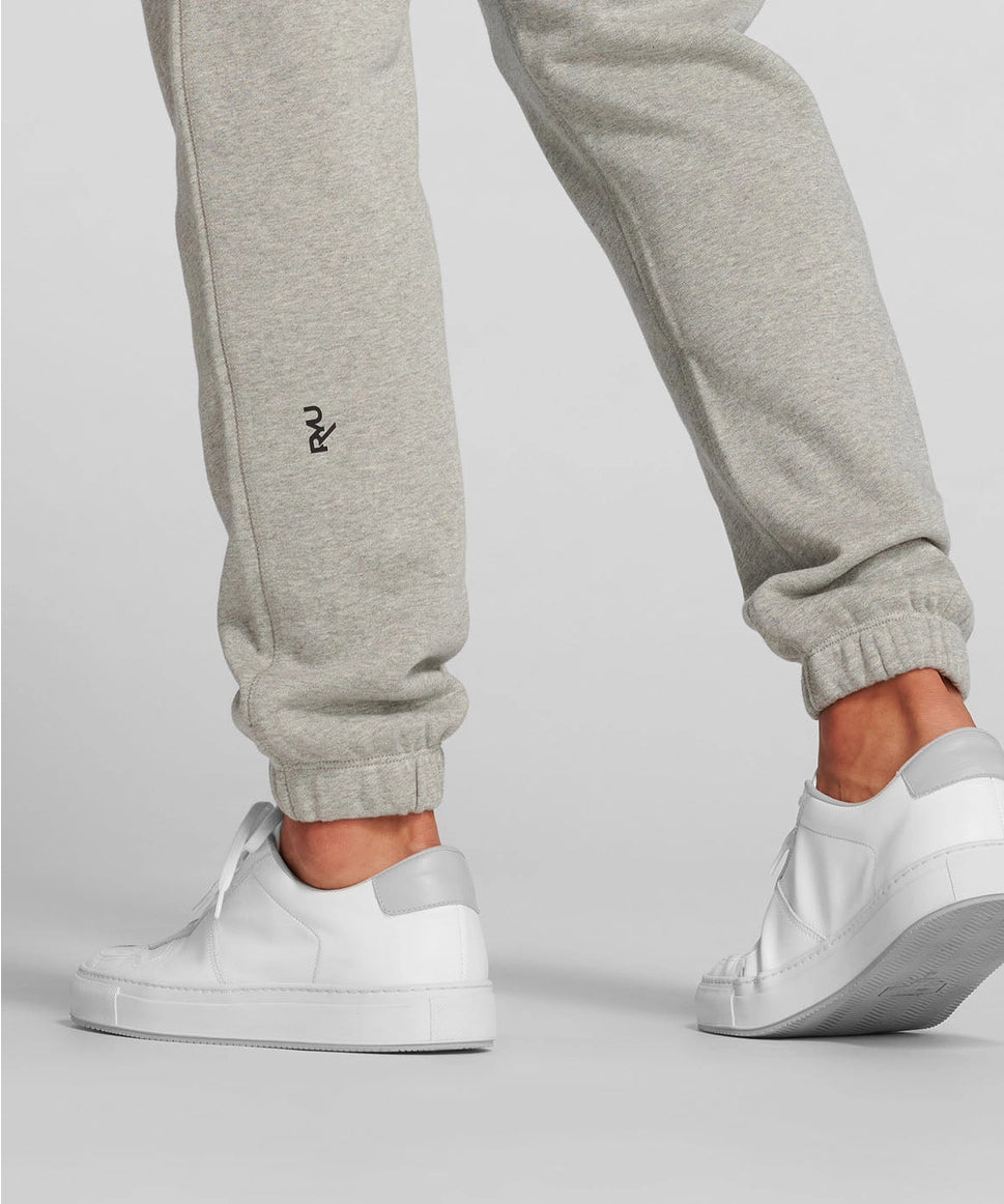 Gray sweatpants with a logo and white sneakers on a light gray background RYU