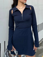 Woman wearing a BOV Active navy blue dress with long sleeves against a white wall.