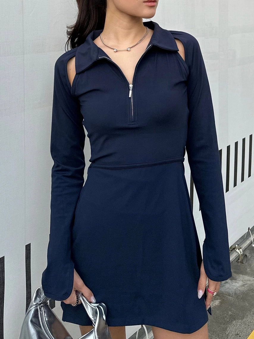 Woman wearing a BOV Active navy blue dress with long sleeves against a white wall.