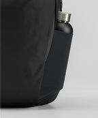 Black backpack with a water bottle in a pocket on a light gray background RYU