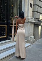 Woman in a beige dress standing in front of a grand building entrance. Standpoint Top