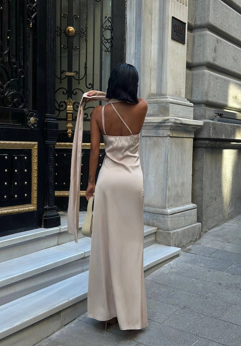 Woman in a beige dress standing in front of a grand building entrance. Standpoint Top