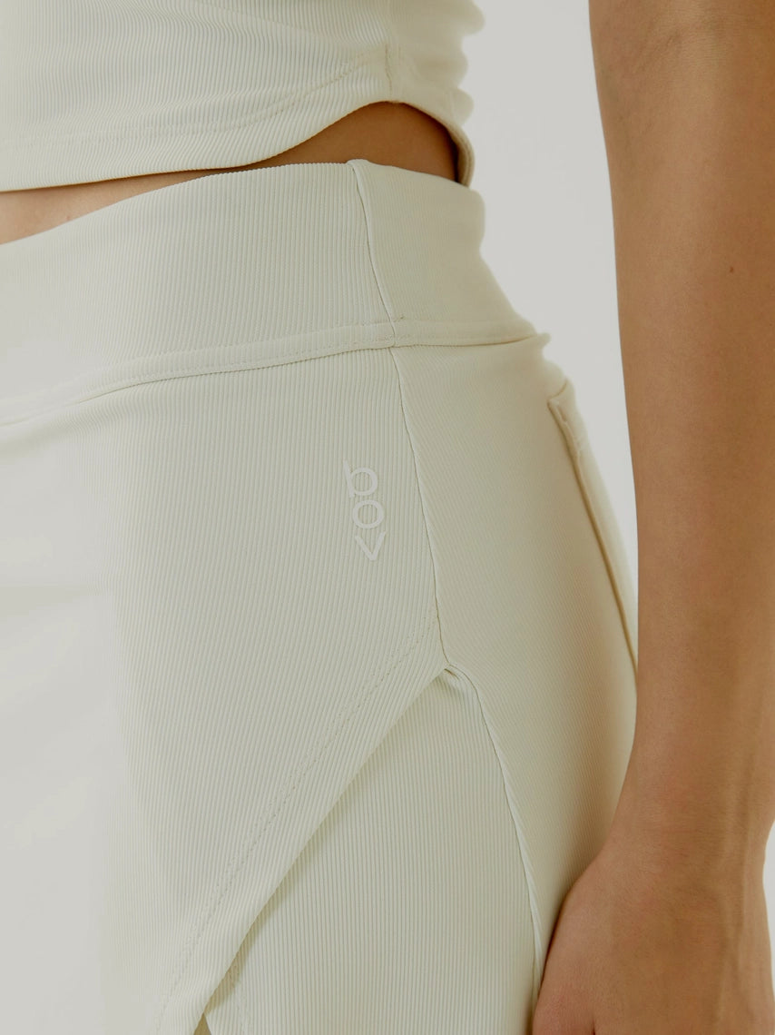 Close-up of a women wearing light-colored cream BOV skirt with a brand logo on a white background