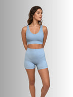 Woman wearing a light blue sports bra and shorts set on a gray background PRIV