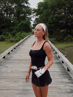 Woman in black athletic wear holding a golf club on a wooden bridge