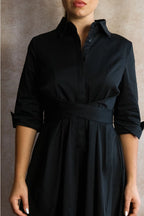 Black dress worn by a person against a neutral background ANNICK