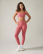 Woman wearing a pink athletic outfit on a plain background rose boreal