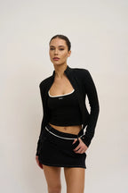 Woman wearing a black outfit with a white logo on a plain background