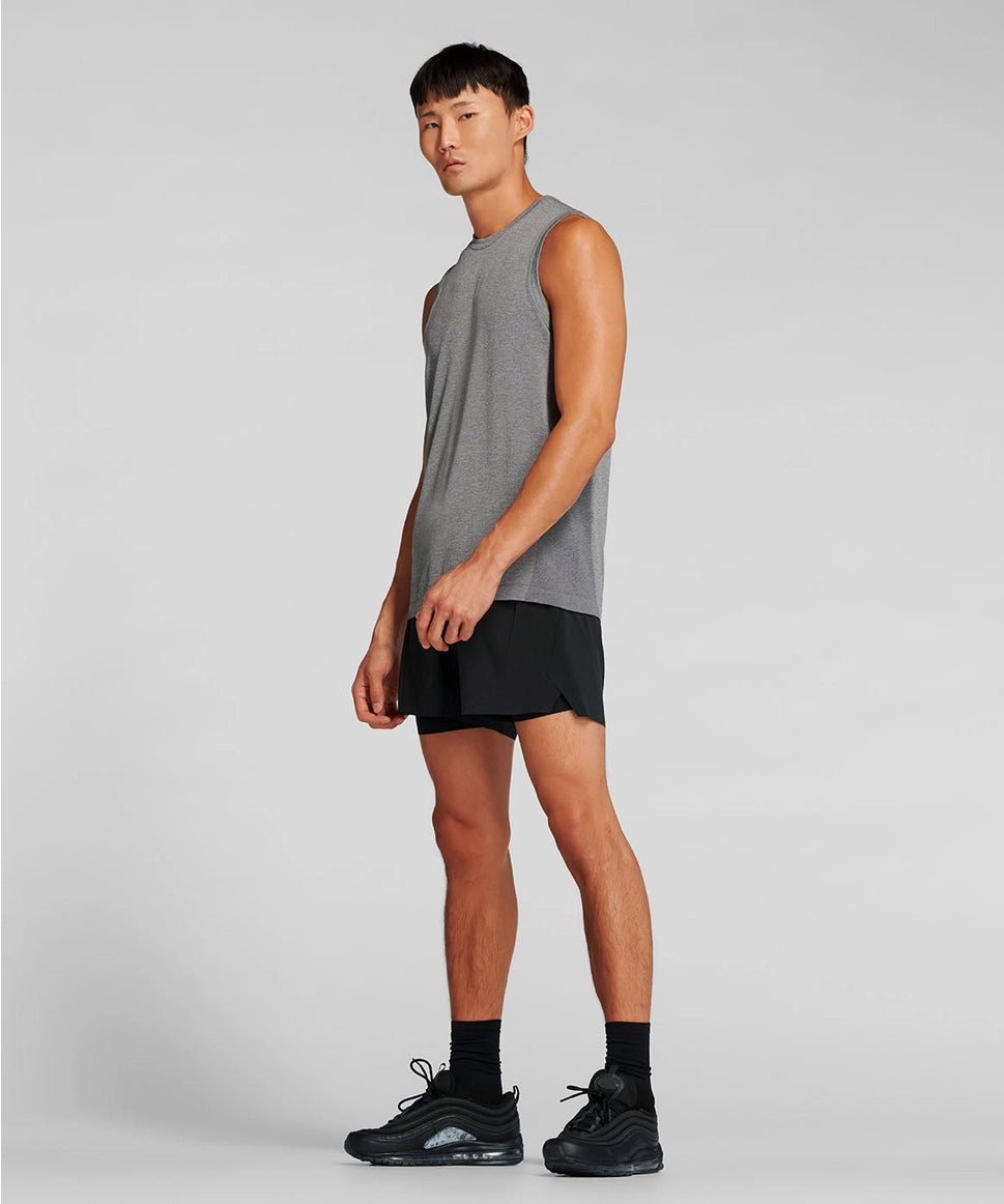 Man wearing a gray sleeveless shirt and black shorts on a light gray background RYU