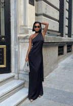 Woman in a black one-shoulder dress standing on a city street. Standpoint Top