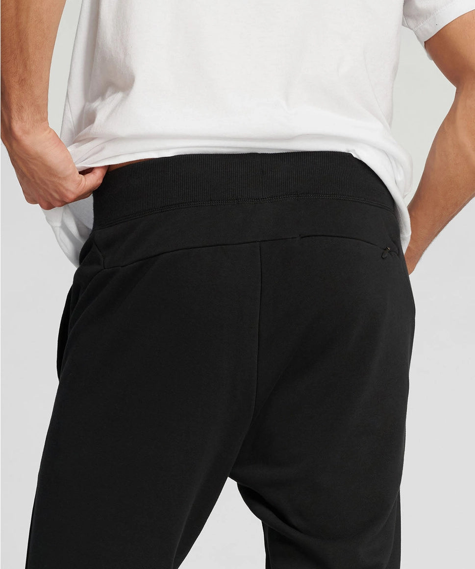 Man wearing black pants and a white shirt on a light gray background RYU