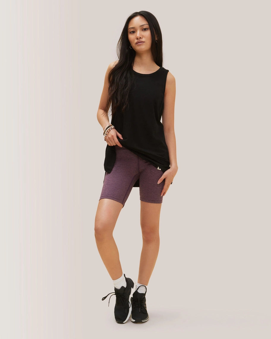 Woman wearing a black sleeveless top and purple shorts on a plain background Rose Boreal