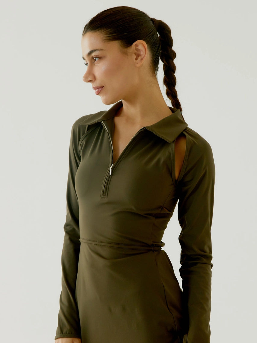 Woman wearing a BOV Active green dress with a zipper detail on a plain background