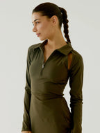 Woman wearing a BOV Active green dress with a zipper detail on a plain background