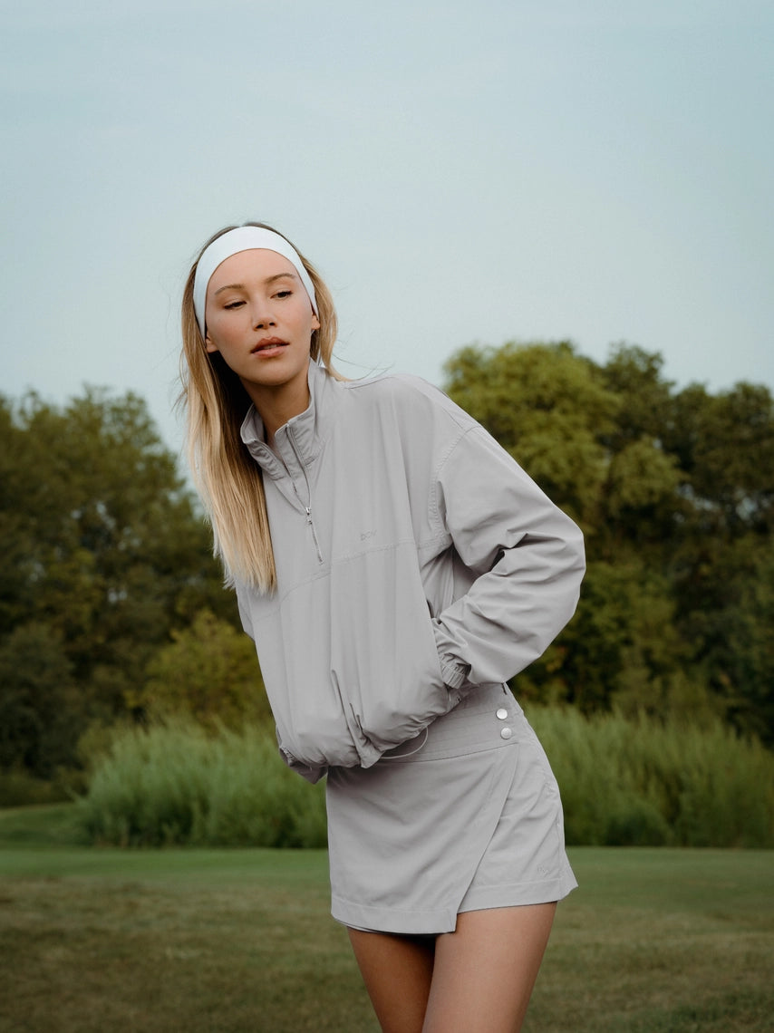 Woman wearing cloud grey BOV Active Mia half zip jacket on golf course