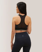 Woman wearing a black sports bra and leggings on a plain background Rose Boreal