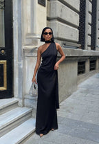 Woman in a black one-shoulder dress standing on a city street. Standpoint Top