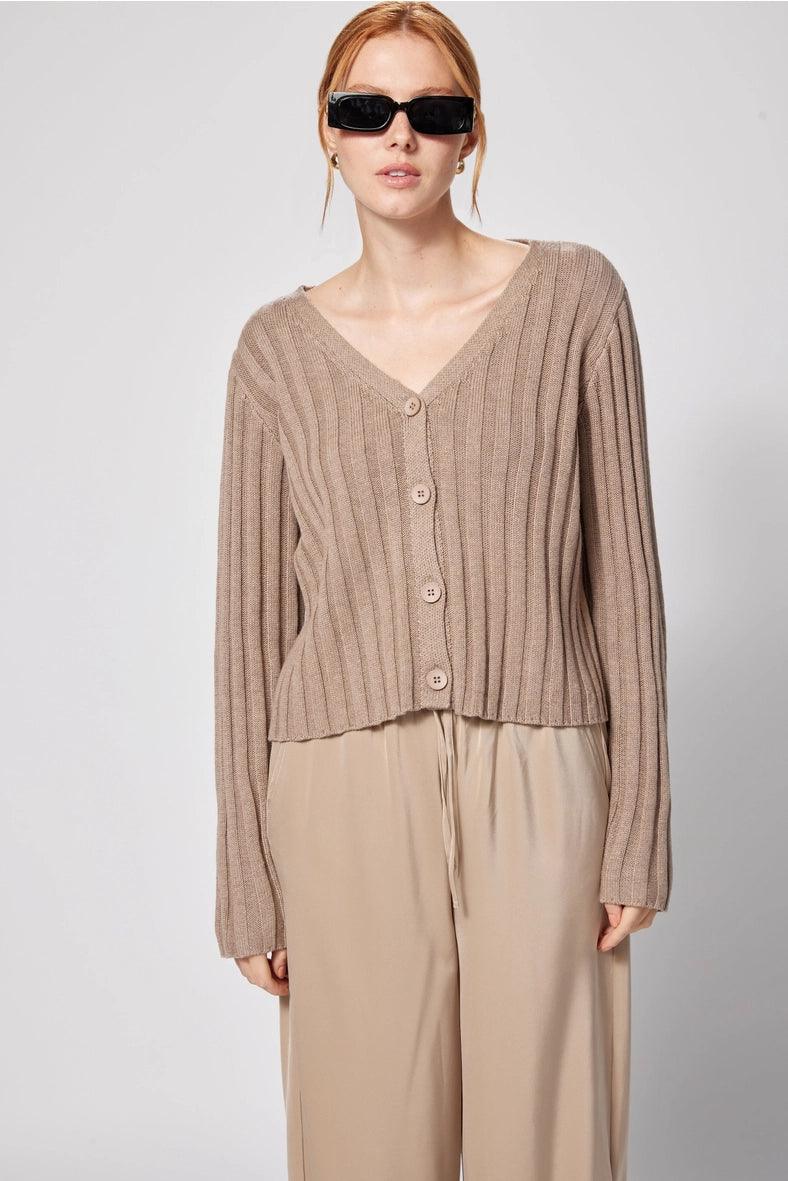 Woman wearing a beige ribbed cardigan and matching pants against a light gray background Amanda Maria