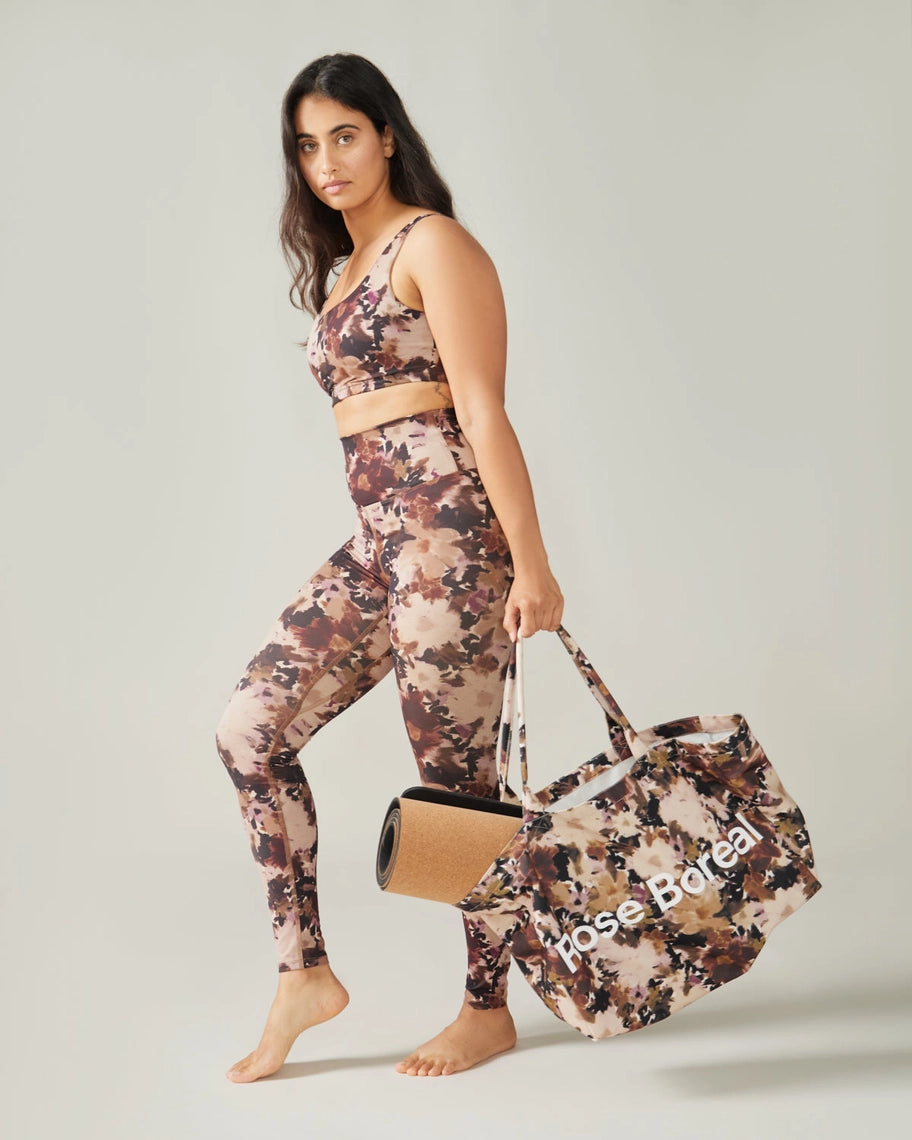 Woman in Rose Boreal floral athletic wear and cap standing outdoors with white in the background