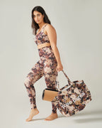 Woman in Rose Boreal floral athletic wear and cap standing outdoors with white in the background