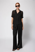 Woman wearing a black outfit with sunglasses on a white background Amanda Maria