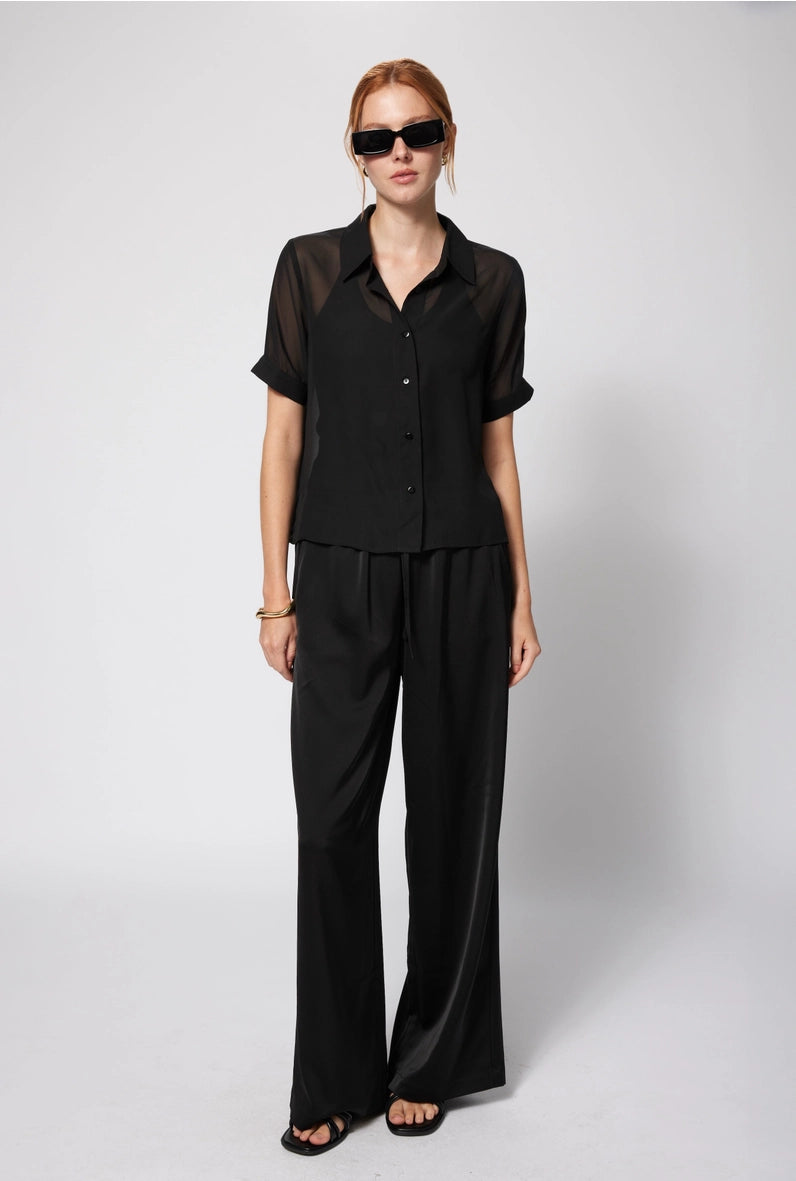 Woman wearing a black outfit with sunglasses on a white background Amanda Maria