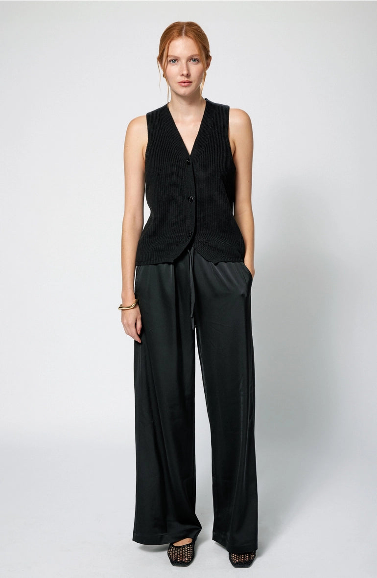 Woman wearing a black sleeveless top and wide-leg pants on a white background Amanda Maria  