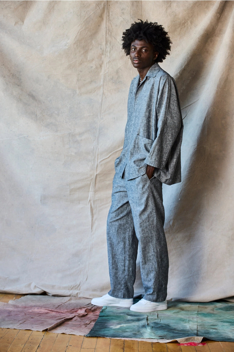 Man wearing a gray jumpsuit standing against a plain background Devlyn van Loon