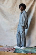 Man wearing a gray jumpsuit standing against a plain background Devlyn van Loon