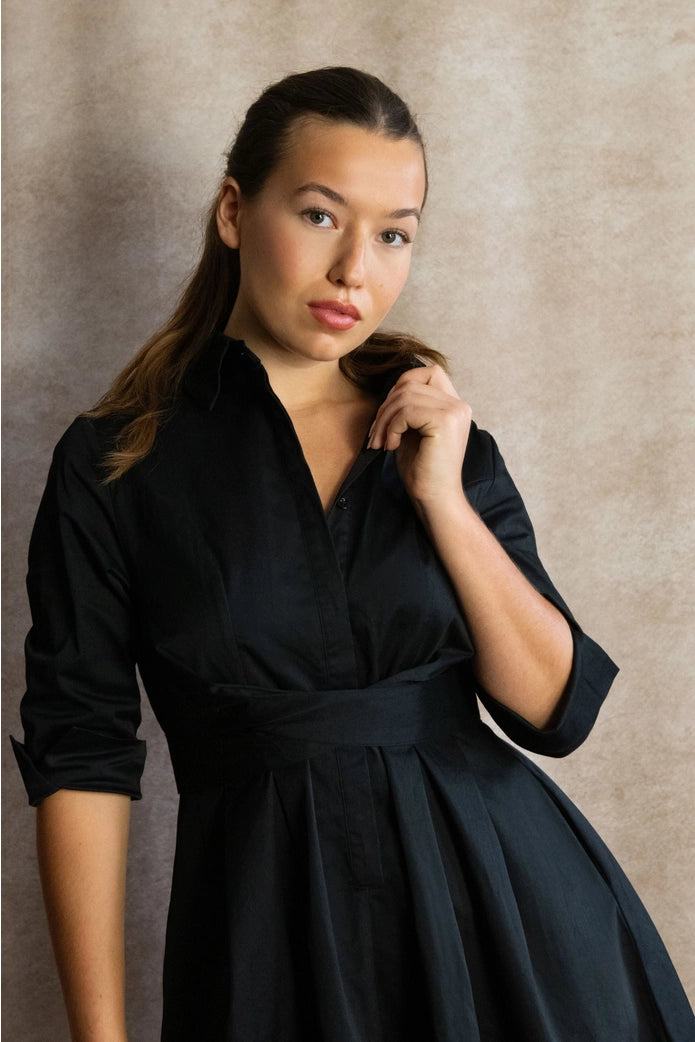 Woman wearing a black dress against a neutral background ANNICK