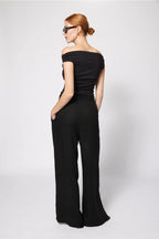 Woman wearing a black off-shoulder jumpsuit on a white background Amanda Maria
