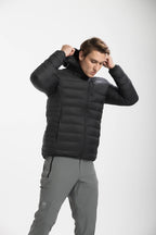 Man wearing a black puffer jacket and gray pants on a white background Aparso