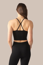 Person wearing a black sports bra and leggings on a beige background