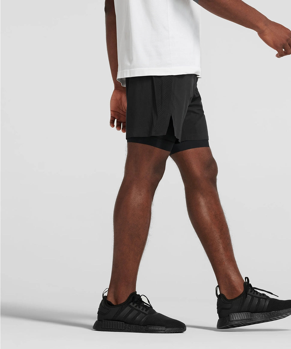 Man wearing black athletic shorts and black sneakers on a light gray background RYU