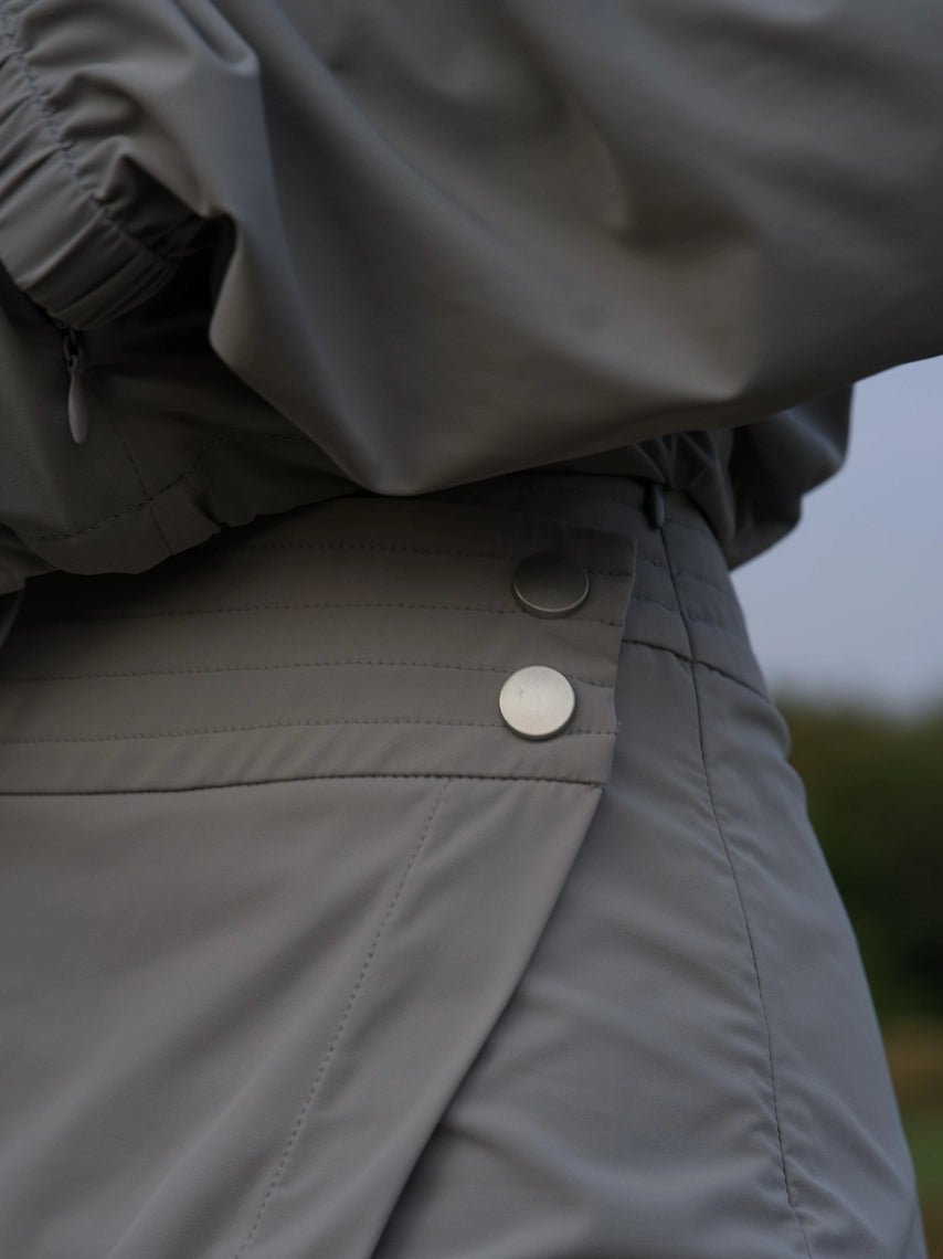 Close-up of a person wearing a gray jacket with a button, blurred background in a grey BOV skirt
