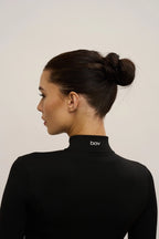Woman wearing a black turtleneck with 'bov' branding on a plain background