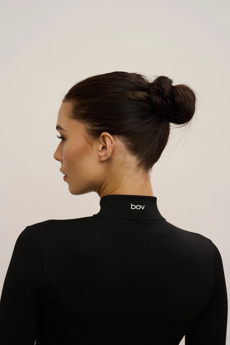 Woman wearing a black turtleneck with 'bov' branding on a plain background