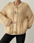 Beige knitted cardigan worn by a person on a plain background ANAZ