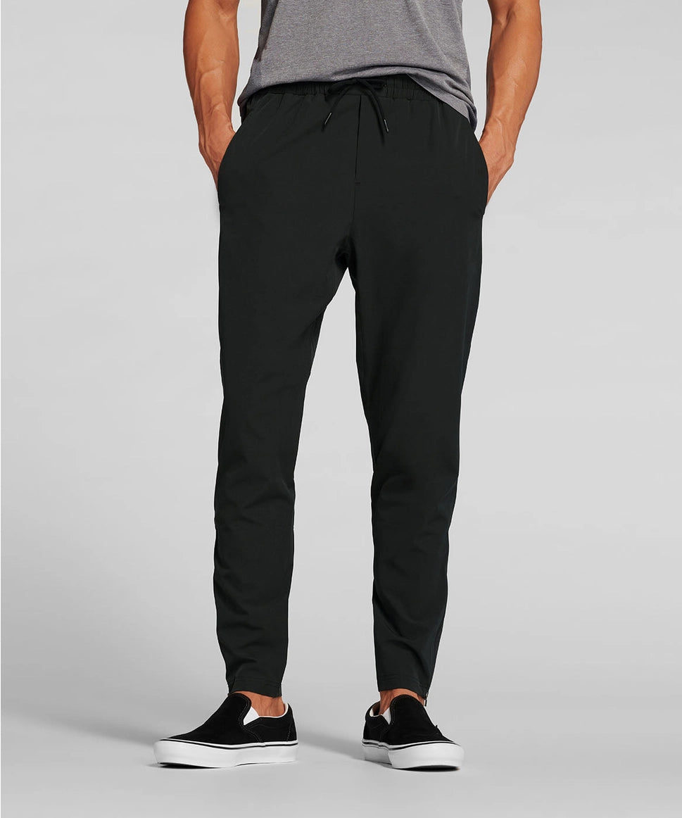 Man wearing black jogger pants and black sneakers on a gray background RYU