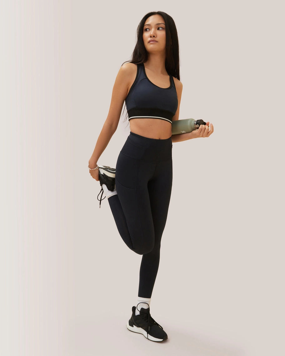 Woman in black athletic wear holding a skateboard against a plain background Rose Boreal