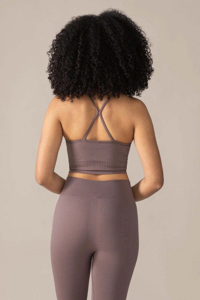 Person wearing a brown sports bra and leggings set on a beige background