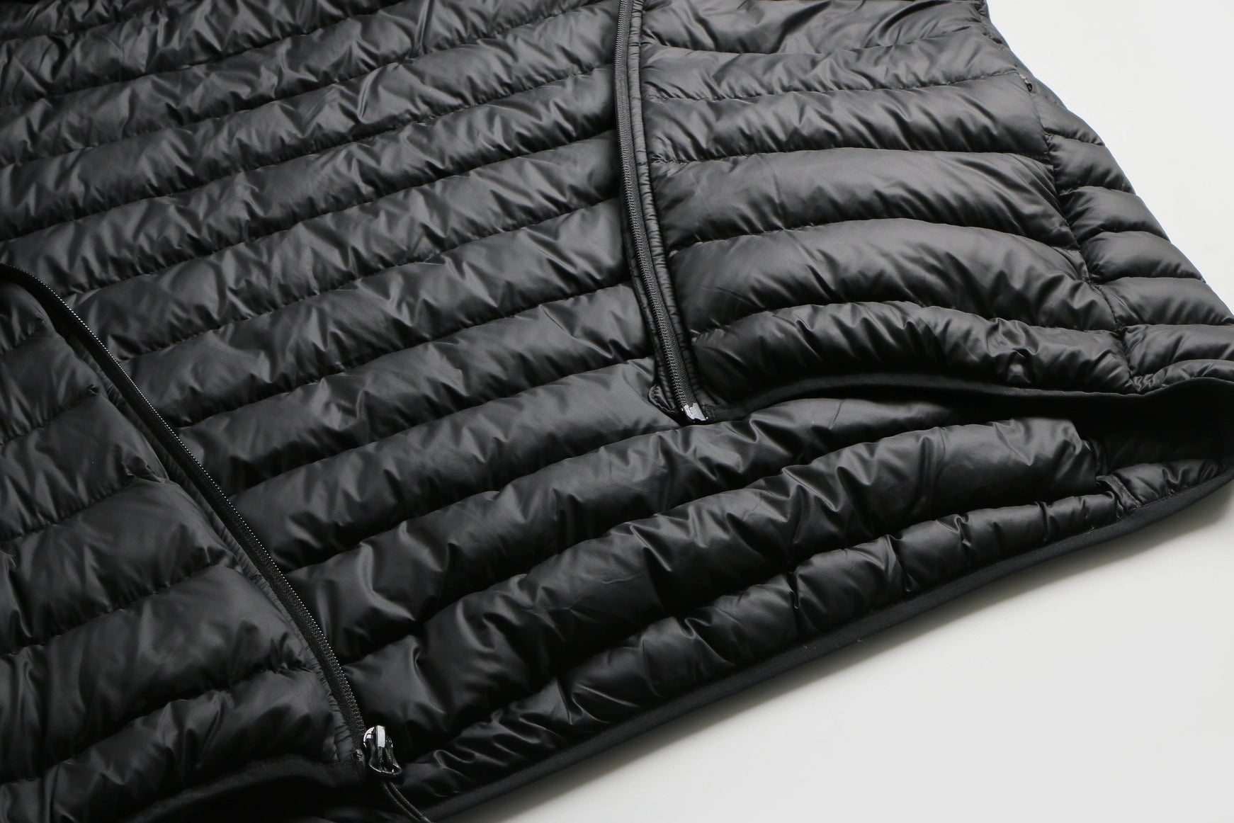 Close-up of a black puffer jacket on a light gray background Aparso