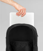 Black backpack with a hand placing a white sheet of paper into it on a gray background RYU