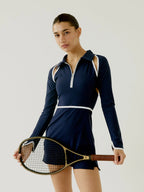 Woman in a BOV Active navy blue tennis dress holding a squash racket against a plain background