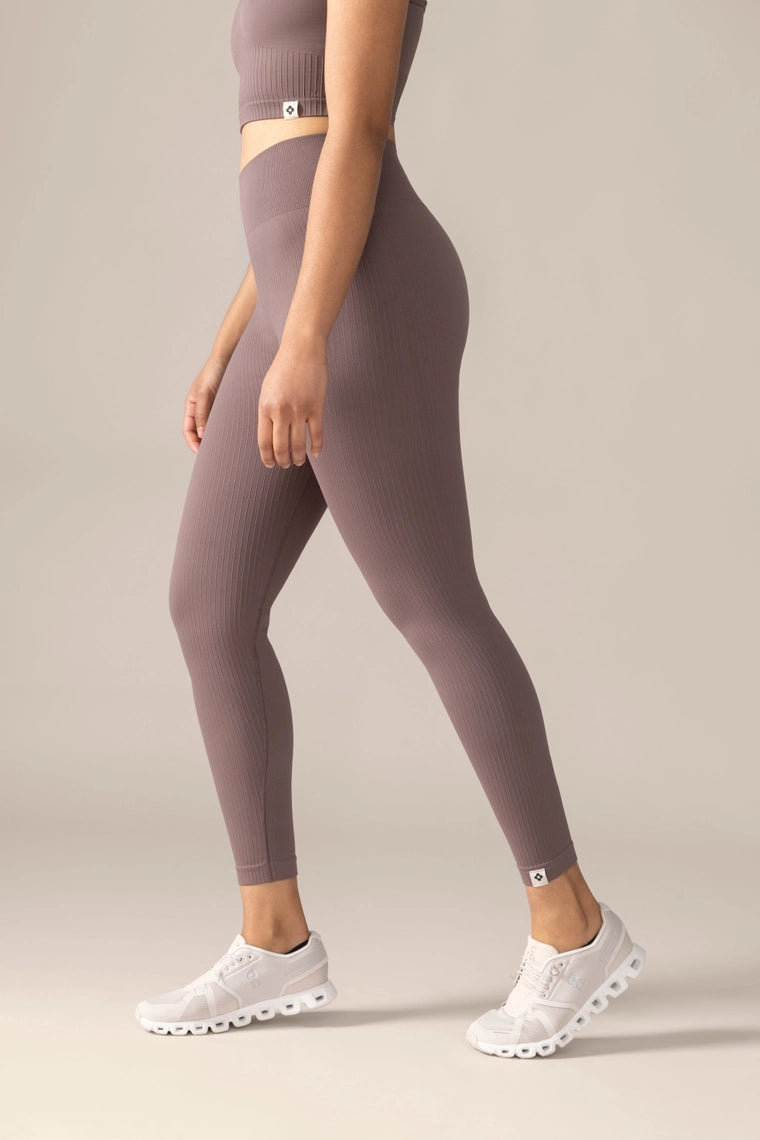 Women wearing a pair of mauve leggings on a plain background