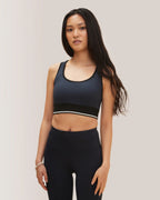 Woman wearing a black sports bra and leggings on a plain background Rose Boreal